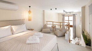 A modern hotel room with a large bed, a small seating area, and a view of the outdoors. - Palm Residences (Kassandra)