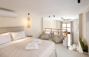Una habitación de hotel moderna con una cama grande, una pequeña zona de estar y vistas al exterior.
