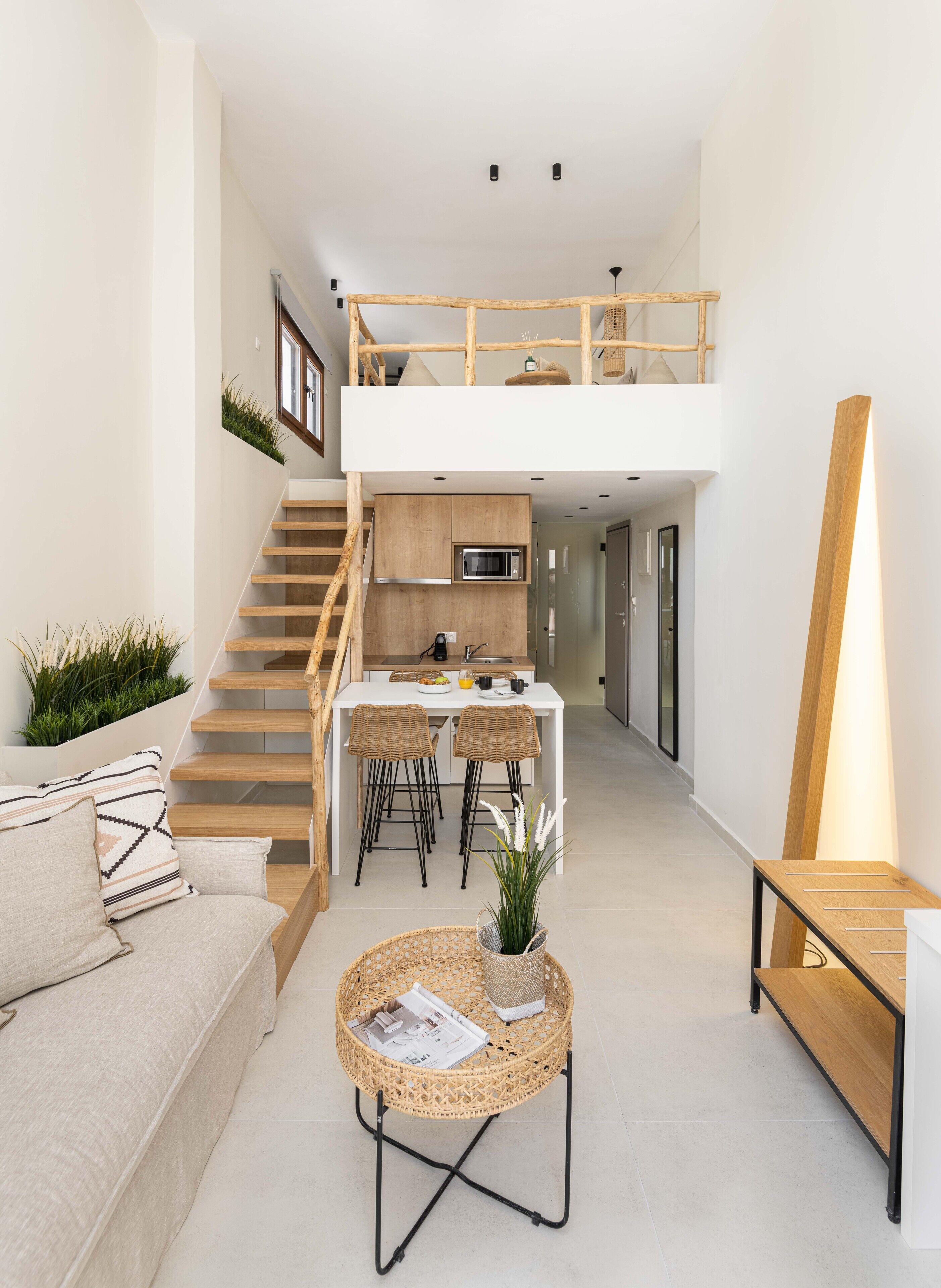Un appartement moderne doté d’une chambre en mezzanine, d’une cuisine et d’un espace de vie comprenant un canapé et une table basse.