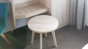 A room with a built-in wardrobe, a small round table, and a trash bin. - Boardinghouse am Borkumkai (Emden)