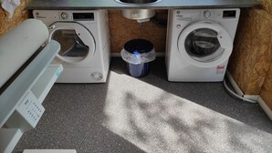 A compact laundry room with two washing machines, a sink, and a window. - Boardinghouse am Borkumkai (Emden)