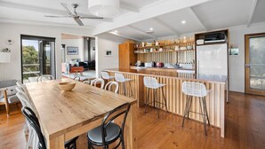 Una cocina moderna con una isla de madera, taburetes blancos y una gran mesa de comedor.
