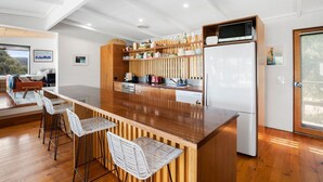 Una cocina moderna con una isla de madera, taburetes de bar y microondas integrado.