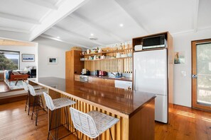 Eine moderne Küche mit einer Holztheke, Barhocker und einer eingebauten Mikrowelle.