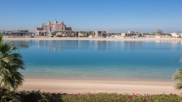 A beachfront hotel with a clear view of the ocean, a large building with a distinctive archway, and a sandy beach. - Maison Privee - Prvt Pool & Beach in Luxury Palm Jumeirah Villa (Dubai)