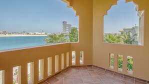 A balcony with a view of the beach and a high-rise building. - Maison Privee - Prvt Pool & Beach in Luxury Palm Jumeirah Villa (Dubai)