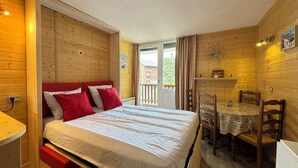 A wooden cabin room with a bed, a small table, and chairs. - 4-person apartment - all comforts <br>Skis at your feet (La Joue du loup - Le Devoluy)
