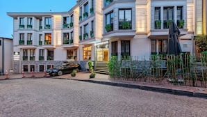 A multi-story hotel with a classic architectural style, featuring balconies with greenery, a cobblestone driveway, and a black car parked in front. - Sultan Hamit Hotel (Istanbul)