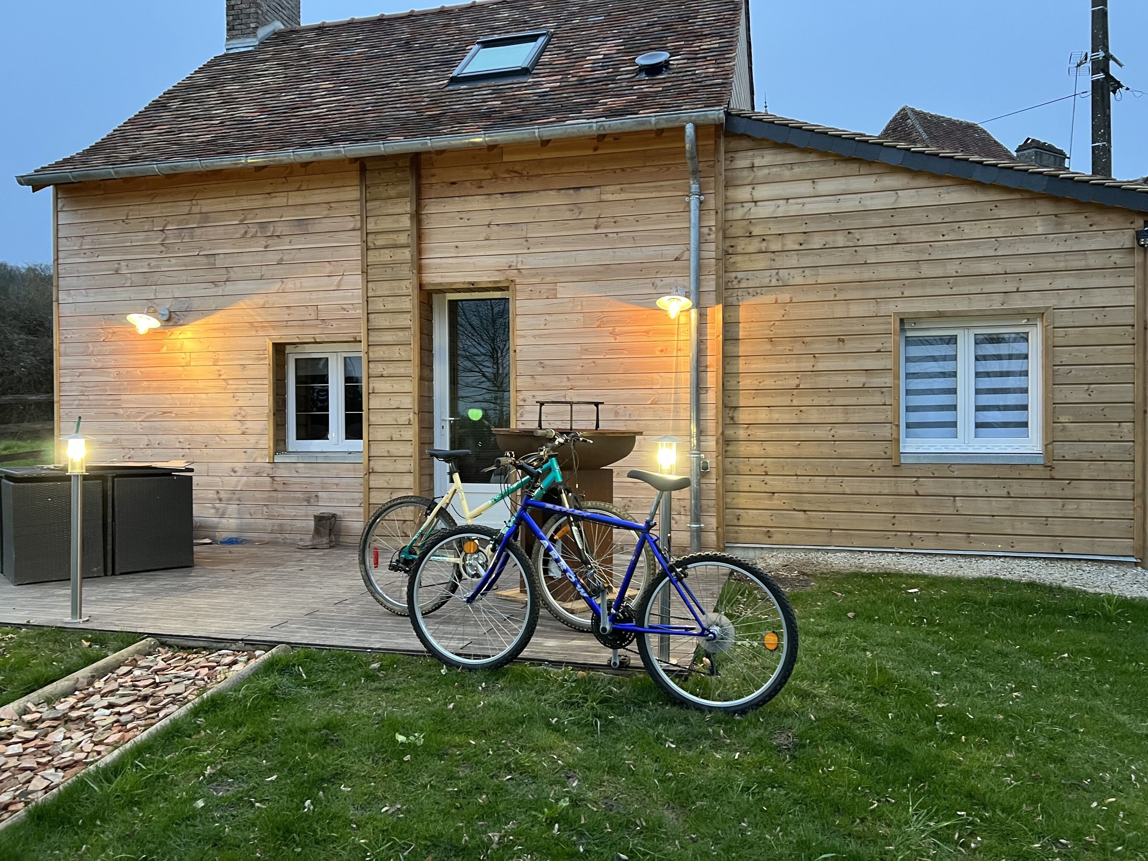 A wooden house with a porch, two bicycles, and outdoor lighting.