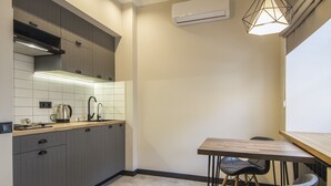 A compact kitchen with grey cabinets, a wooden countertop, a sink, and a hanging pendant light. - Idea Design Apart-Hotel Prorizna (Kyiv)