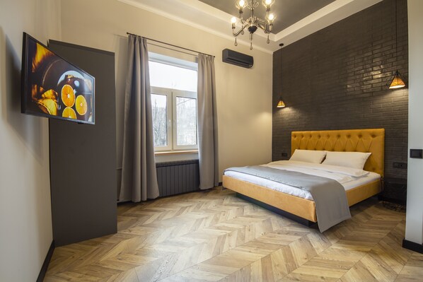 A modern bedroom with a large bed, a television on the wall, and a window with curtains. - Idea Design Apart-Hotel Prorizna (Kyiv)