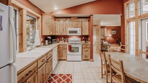 A kitchen with wooden cabinets, a white stove, and a dining table with chairs.