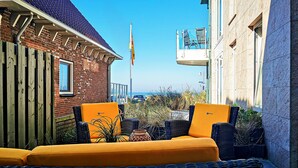 A balcony with wicker furniture and a view of the sea. - Flat Fish (Egmond aan Zee)