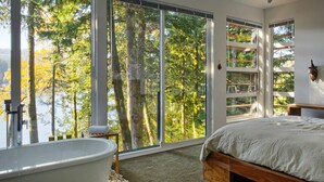 A bedroom with a large window, a bathtub, and a bed. - Silver Lake 83 - Spectacular Dream Home Overlooking Silver Lake (Deming)