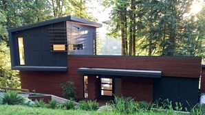 A modern two-story house with a flat roof and a combination of dark and light wood paneling. - Silver Lake 83 - Spectacular Dream Home Overlooking Silver Lake (Deming)