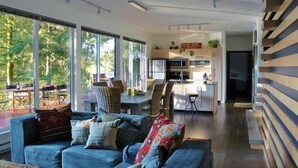 A modern living room with a sofa and chairs, a dining area with a table, and a kitchen with a central island. - Silver Lake 83 - Spectacular Dream Home Overlooking Silver Lake (Deming)