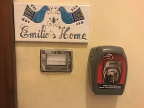 Un pany de claus fixat a la paret, amb una inscripció que diu 'Casa de l'Emilio' i un cartell decoratiu a dalt.