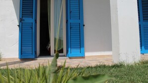 A building with blue shutters and a visible doorway. - Room in Guest Room - S'olivariu Village Affittacamere - King Room With Roll-in Shower (Piscinas)