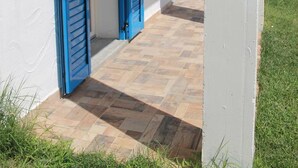 A corridor with two open doors, each with blue shutters, leading to a covered outdoor area. - Room in Guest Room - S'olivariu Village Affittacamere - King Room With Roll-in Shower (Piscinas)