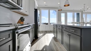 Una cocina moderna con electrodomésticos de acero inoxidable, una isla grande e iluminación colgante.