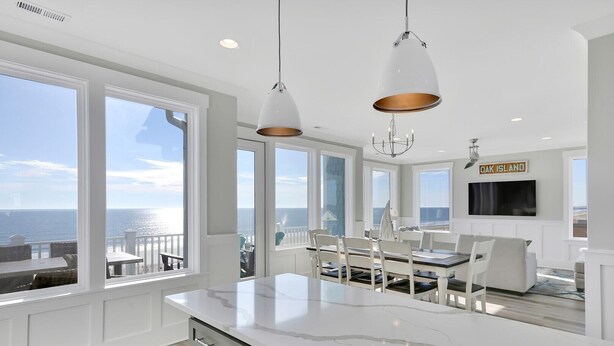 Una cocina moderna con ventanas amplias, un comedor y vista al océano.