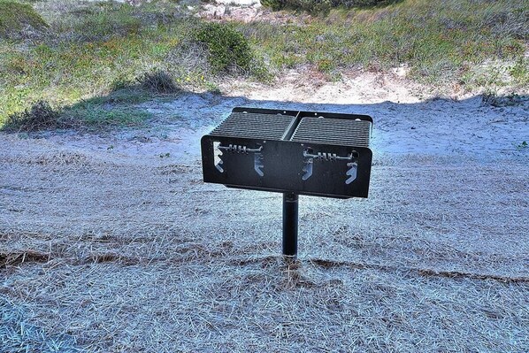 A black metal sign with two rectangular panels on a pole, set in a grassy area with sparse vegetation. - Experience luxury at 'Gratitude' in Oak Island, a spacious 5-bedroom ocean-view retreat. (Oak Island)