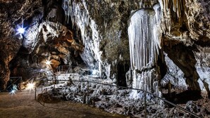 Una cueva con estalactitas y estalagmitas, barandillas de metal y un interior bien iluminado.