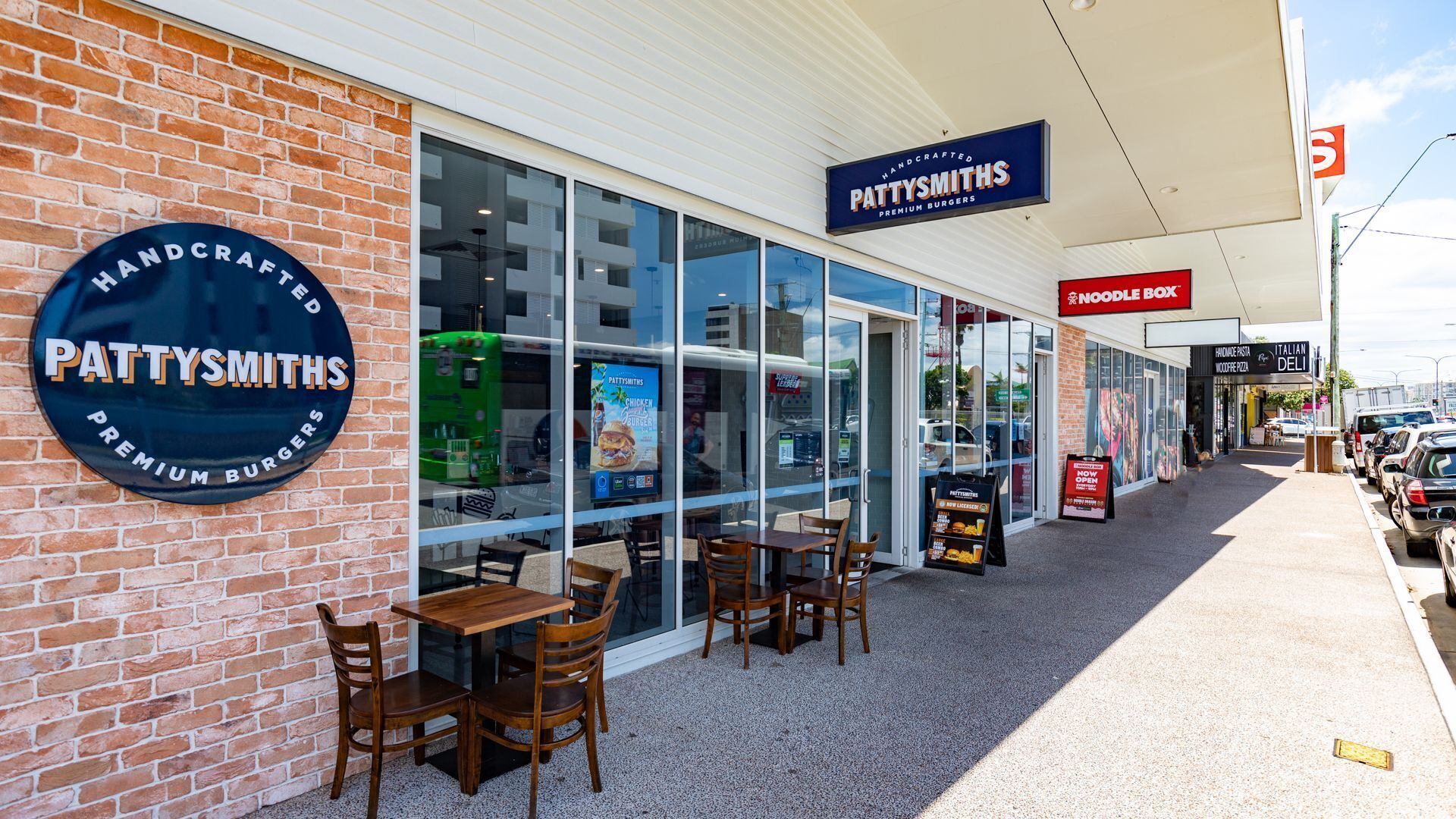 A brick building with a large glass window and a sign reading "PATTYS SMITHS PREMIUM BURGERS".