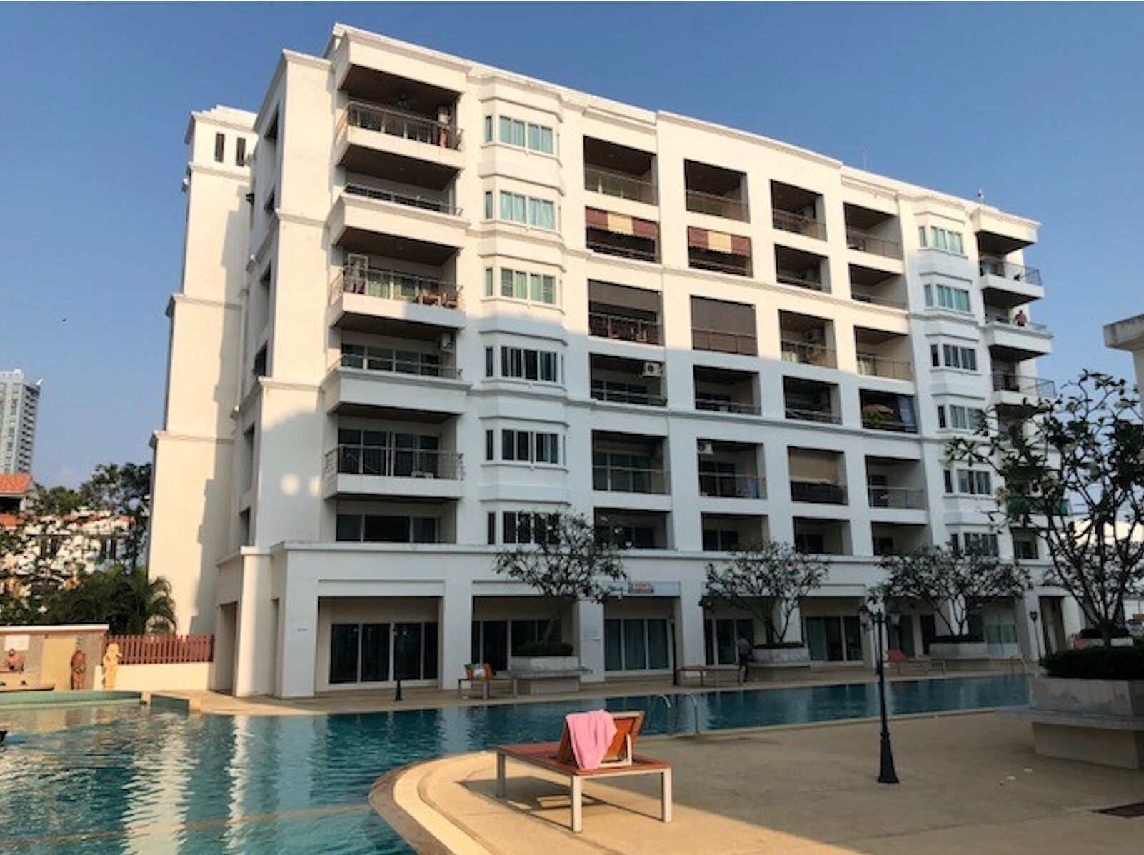 Un edificio residenziale a più piani con balconi, piscina e area relax.