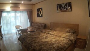 Una habitación de hotel con una cama grande, un ventilador de techo, un escritorio y una silla.