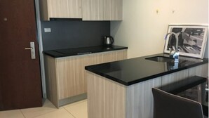 A compact kitchen with a black countertop, wooden cabinets, and a small island with a sink.