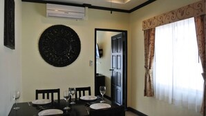 A dining area with a round black wall decoration, a dining table set with plates and glasses, and a window with patterned curtains. - Baan Suan Lalana Sa Floor 5 Room 516 (Pattaya)