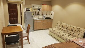 A compact living space with a kitchenette, a dining area with a table and chairs, and a sofa. - Jomtien Beach Condomijium S1 F5 R37 (Pattaya)