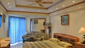 A hotel room with a bed, a sofa, a desk, and a ceiling fan. - Jomtien Beach Condominium A2 F13 R4 (Pattaya)