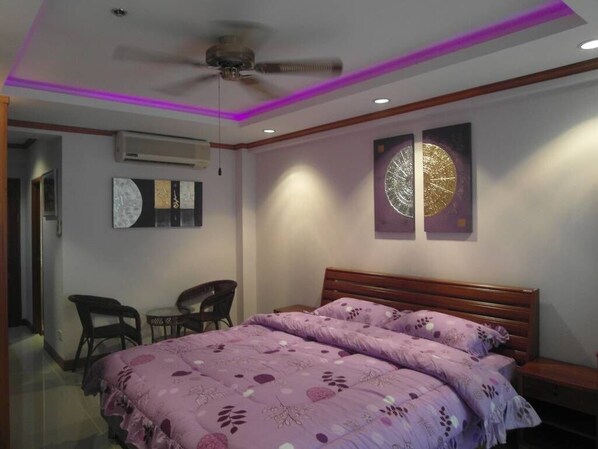 A bedroom with a bed, a ceiling fan, and two wall-mounted air conditioning units.