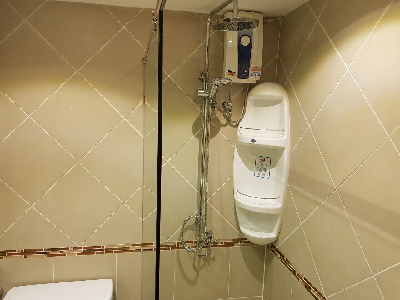 A bathroom with a shower, toilet, and a tiled wall.