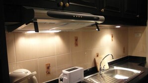 A kitchen with a black countertop, a stainless steel sink, a white toaster, and a microwave. - Jomtien Beach Condominium Jbc A2 F4 R28 (Pattaya)