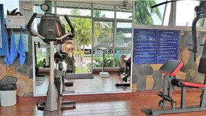 A gym with exercise equipment, a large window, and a stone wall. - Jomtien Beach Condominium Jbc A2 F4 R28 (Pattaya)
