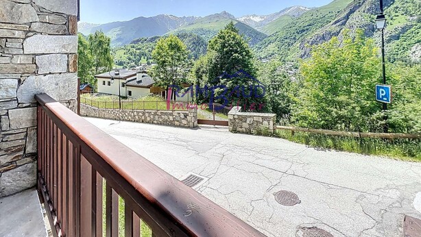 Ein Steinhaus mit einem hölzernen Balkon mit Blick auf eine gebirgige Landschaft.