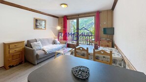 Ein gemütliches Zimmer mit einer Couch, einem Tisch und einem Fernseher.