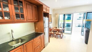 Une cuisine moderne avec des meubles en bois, un évier en acier inoxydable et un coin repas comprenant une table et des chaises.
