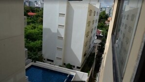 Une vue d’un immeuble résidentiel doté d’une piscine, entouré de verdure et d’autres bâtiments.