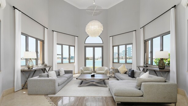A spacious living room with a large sofa set, a coffee table, and a view of the sea through large windows. - Maison Privee - Palm Jumeirah Beach Front XL Villa w/Prvt Pool (Dubai)