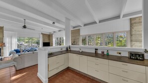 Une cuisine moderne avec des meubles blancs, un plan de travail en bois et une grande fenêtre ornée de vitraux.