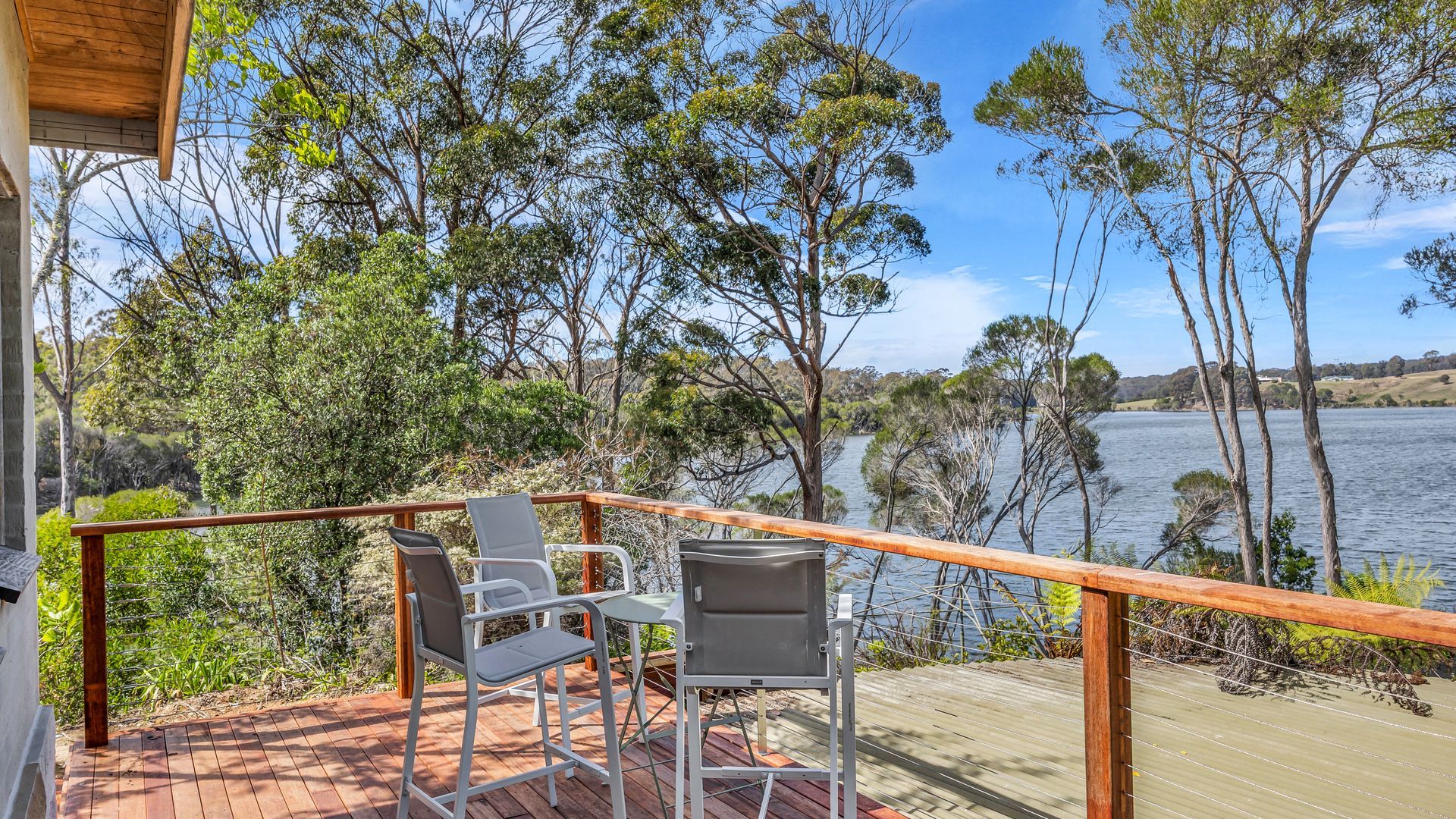 A deck with outdoor seating overlooking a lake and dense foliage.