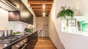 A narrow kitchen with a brick wall, wooden beams, and a hanging plant. - Venice apartment with breath-taking Grand Canal view (Venecia)
