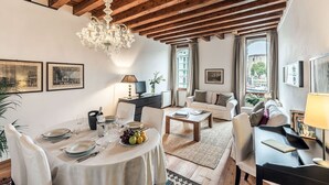 A spacious living room with a high wooden ceiling, a chandelier, and a dining area set for a meal. - Venice apartment with breath-taking Grand Canal view (Venecia)