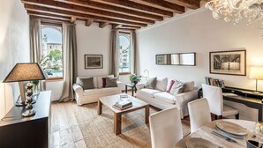 A cozy living room with a wooden ceiling, two sofas, a coffee table, and a dining area with a table set for two. - Venice apartment with breath-taking Grand Canal view (Venecia)