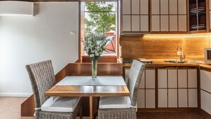Un comedor con una mesa de madera y sillas de mimbre, un jarrón con flores y vistas al exterior a través de una ventana.
