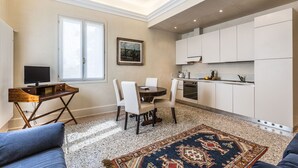 Un espacio habitable compacto con comedor, kitchenette y un amplio ventanal que proporciona luz natural.